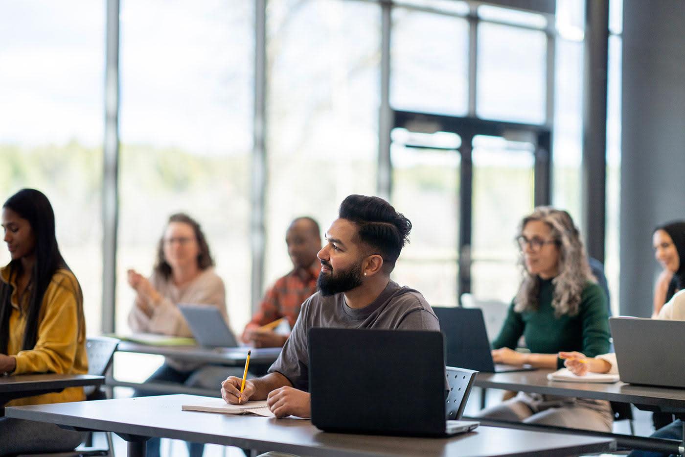 Diverse group of executive education students in a modern classroom with laptops